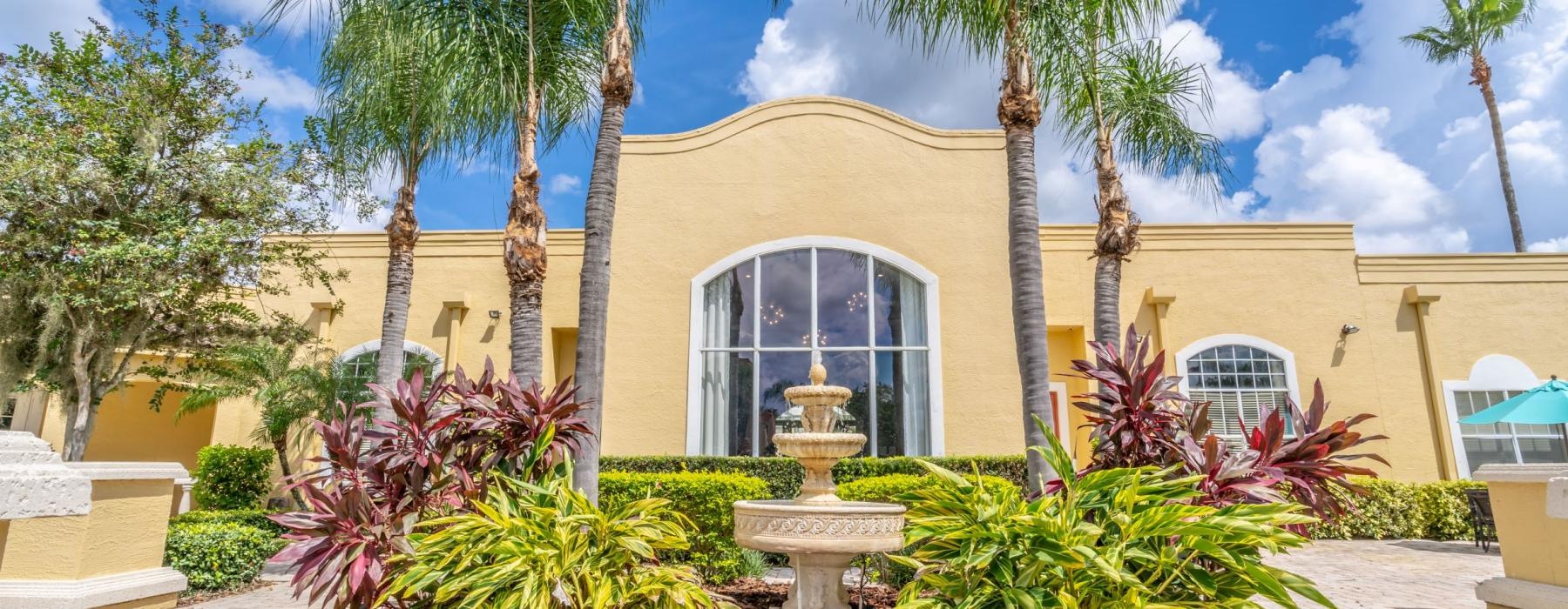 a building with palm trees and a fountain in front of it