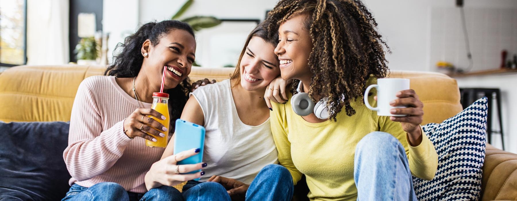 a group of women sitting on a couch looking at a phone