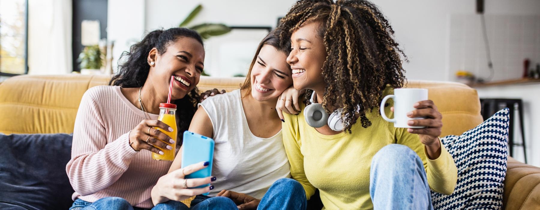 a group of women sitting on a couch looking at a phone